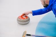 From above of crop concentrated player in uniform choosing trajectory of stone movement while playing curling on ice rink