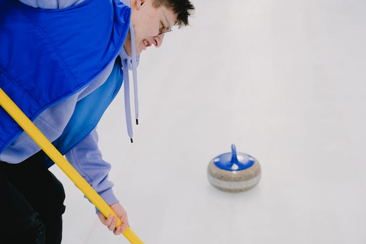 Man Sweeping Ice During Curling Game