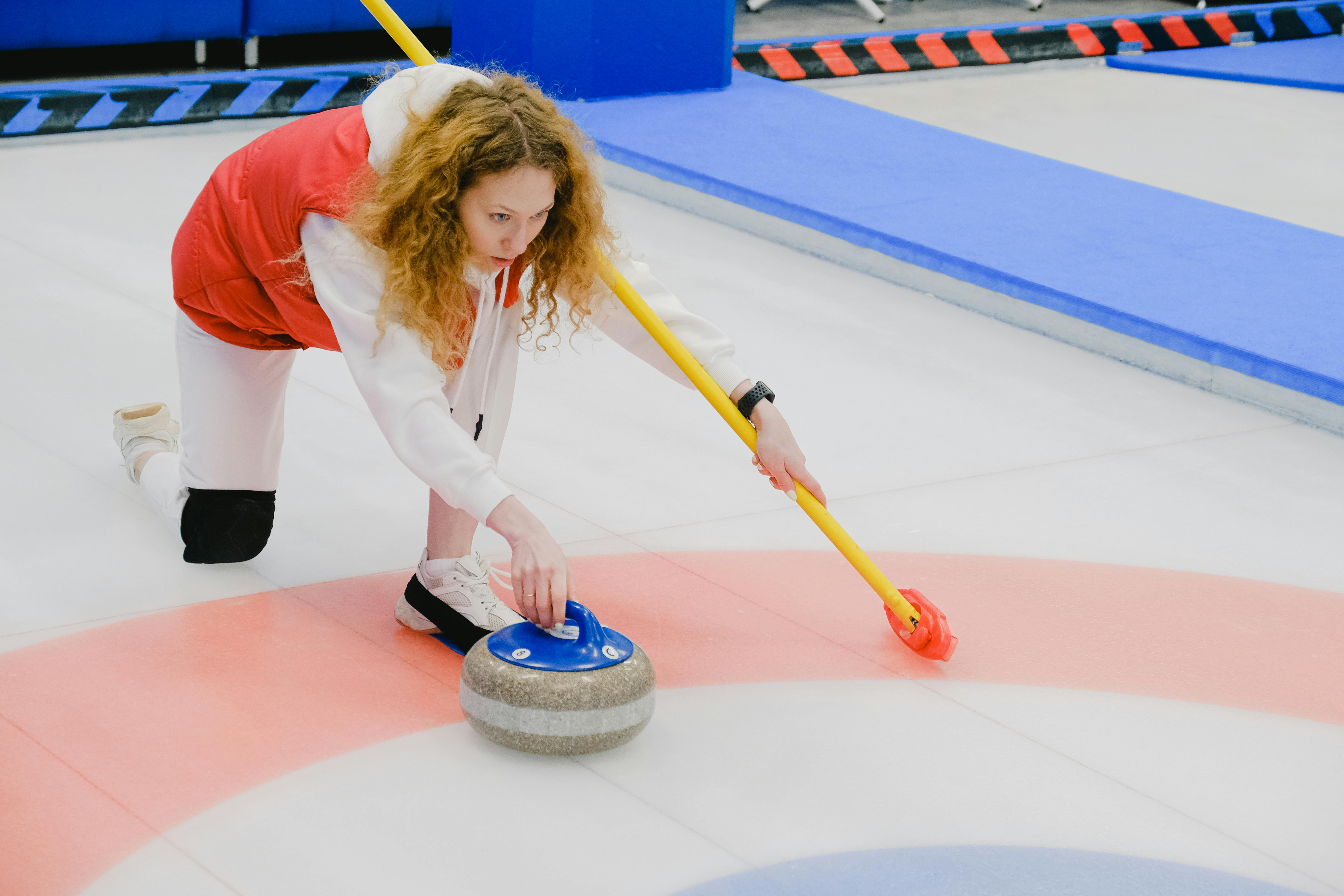 determined woman throwing curling stone