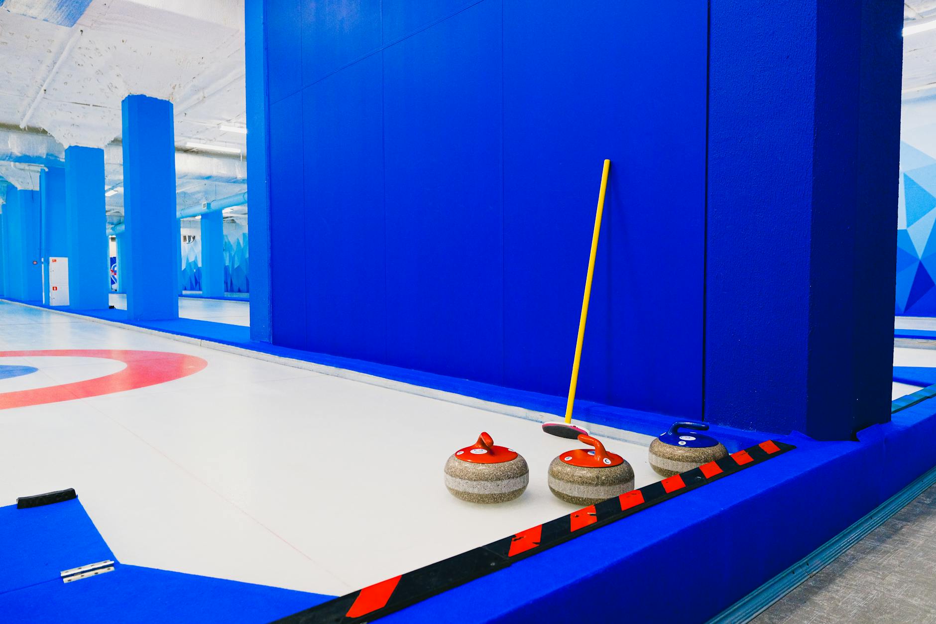 Curling stones and broom near wall