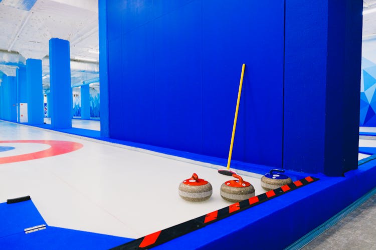 Curling Stones And Broom Near Wall