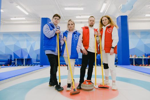 Sportspeople with curling equipment on ice