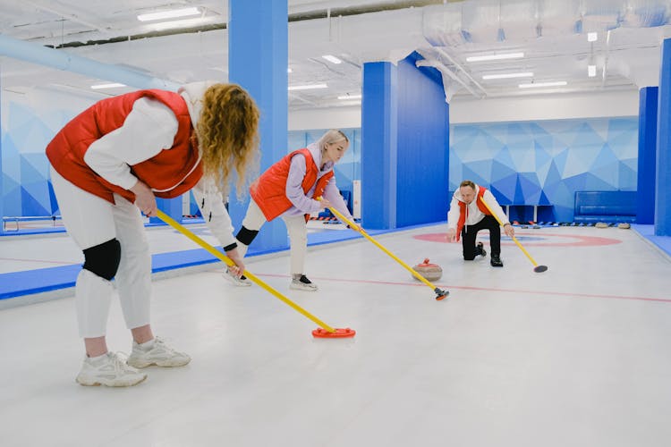 Team Playing Curling On Ice Sheet