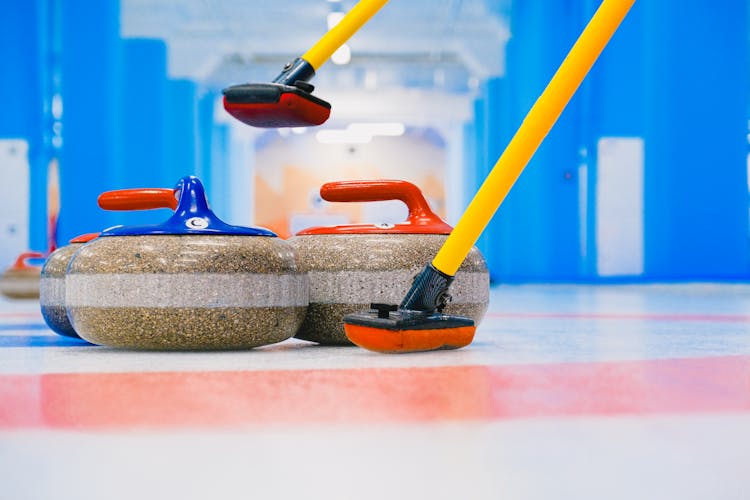 Curling Stones With Brooms In House