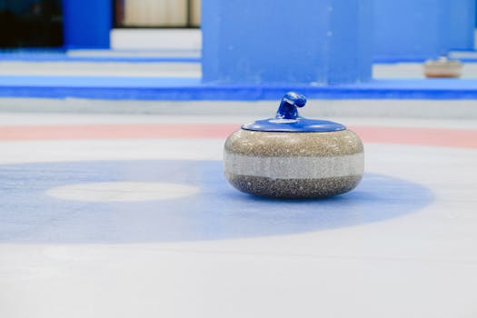 A close-up view of a curling stone on a vibrant indoor ice rink with colorful circles.
