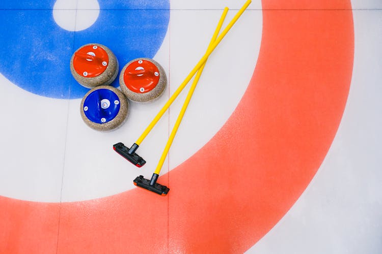 Curling Stones And Brooms In Ice Arena