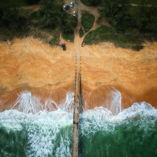 Aerial view of surf breaking on a sandy shoreline — photo by Pok Rie on Pexels
