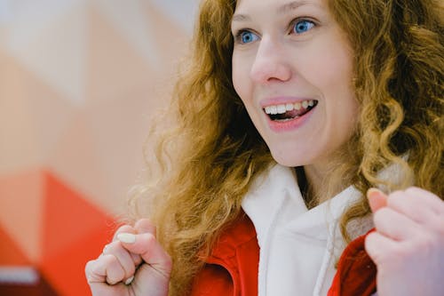 Exited attractive female with curly hair looking away with amazement and clenched fists while rooting for team during sportive game