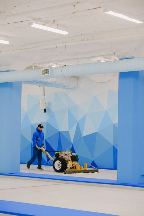 Free Distant man with professional ice scrapper machine walking on ice sheet near wall in arena while preparing for sportive game Stock Photo