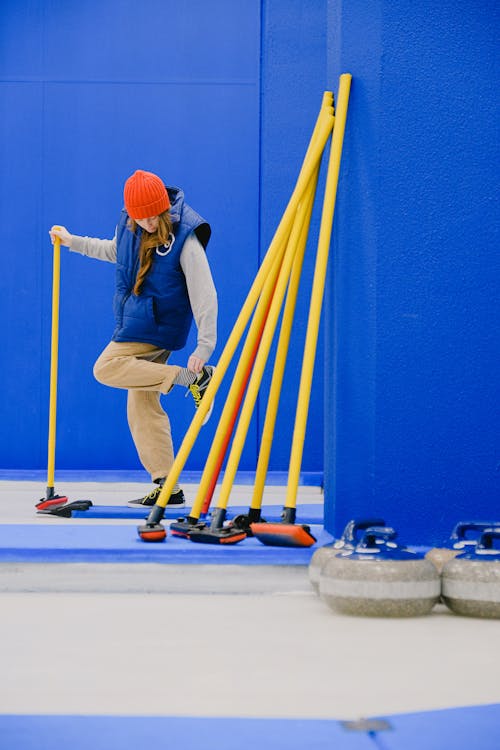 Sportswoman with brush adjusting shoe in curling sheet