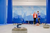 Men inviting teammate in curling arena