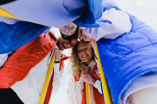 Low angle of cheerful curling team supporting each other in embrace during game
