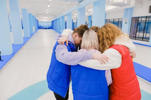 High angle of anonymous team embracing each other while standing in spacious light gym