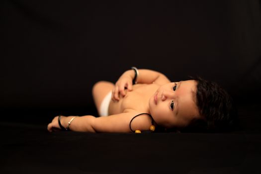 Charming baby lying on a dark surface, capturing innocence and warmth.