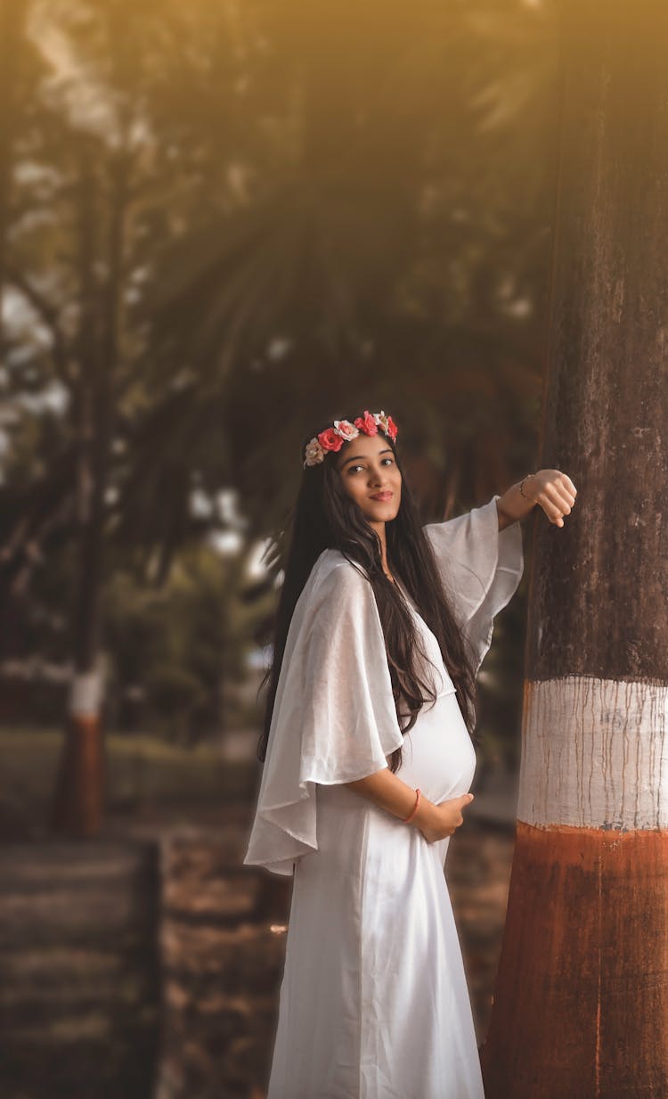 Pregnant Woman In White Dress Standing Beside Brown Wooden Post