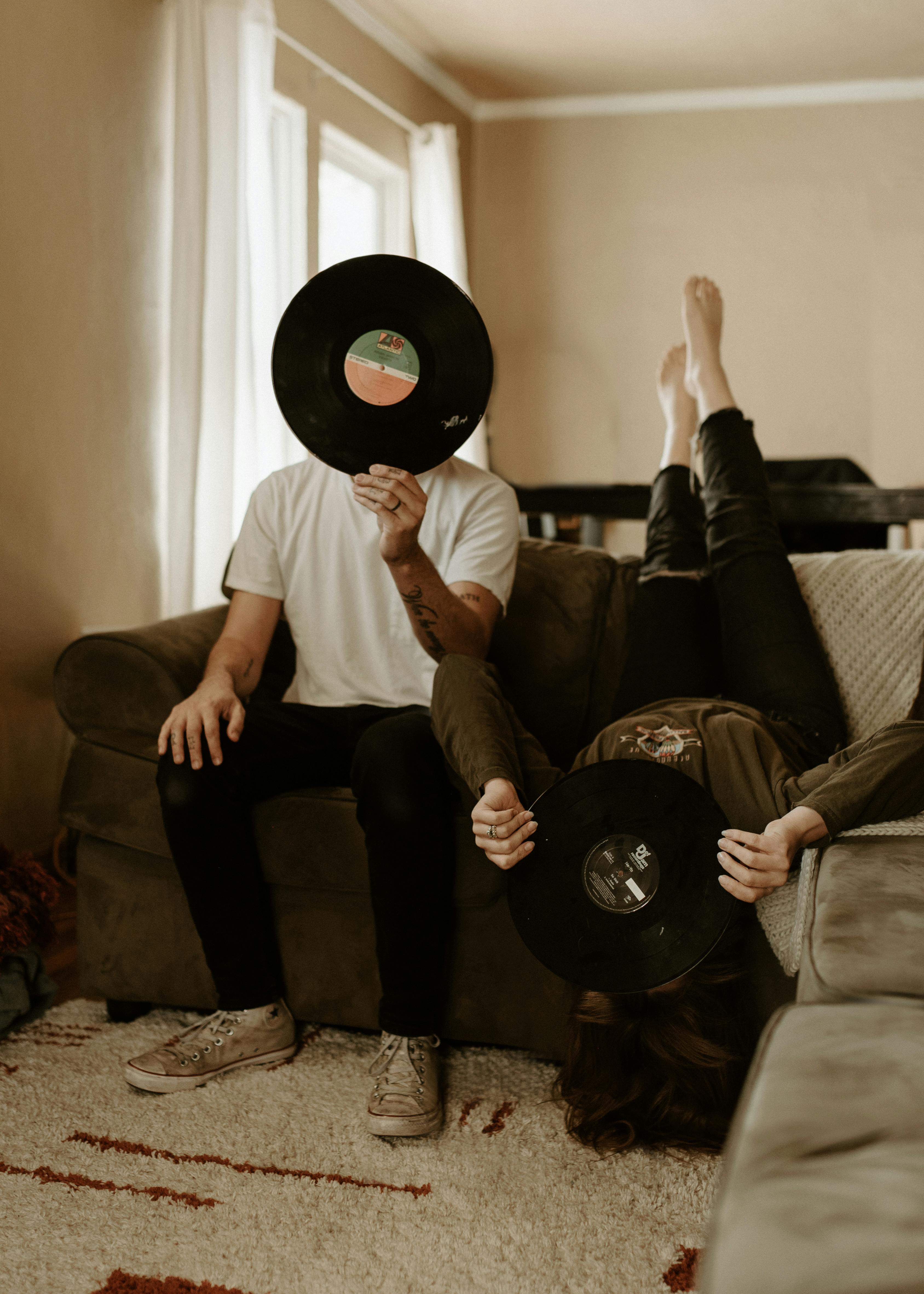 man and woman holding vinyl records against faces