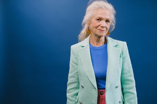 Free Aged content female in stylish jacket looking at camera while standing against blue background Stock Photo