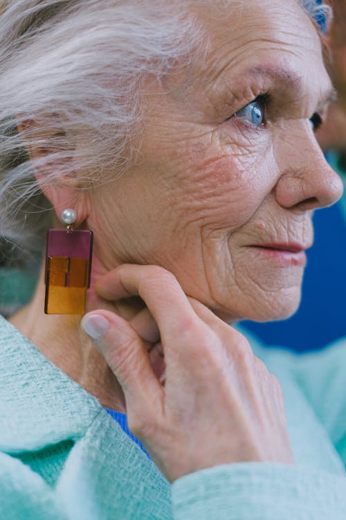 Aged lady touching earring and looking away