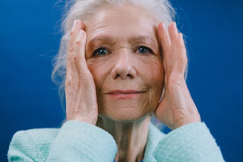 Old lady touching temples in studio