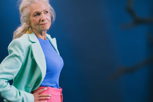 Free Senior lady in trendy outfit looking away against blue background with hands on waist Stock Photo