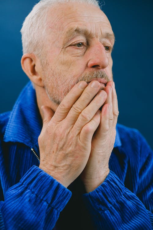 Thoughtful elderly man covering mouth