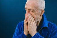 Stressed elderly man covering mouth