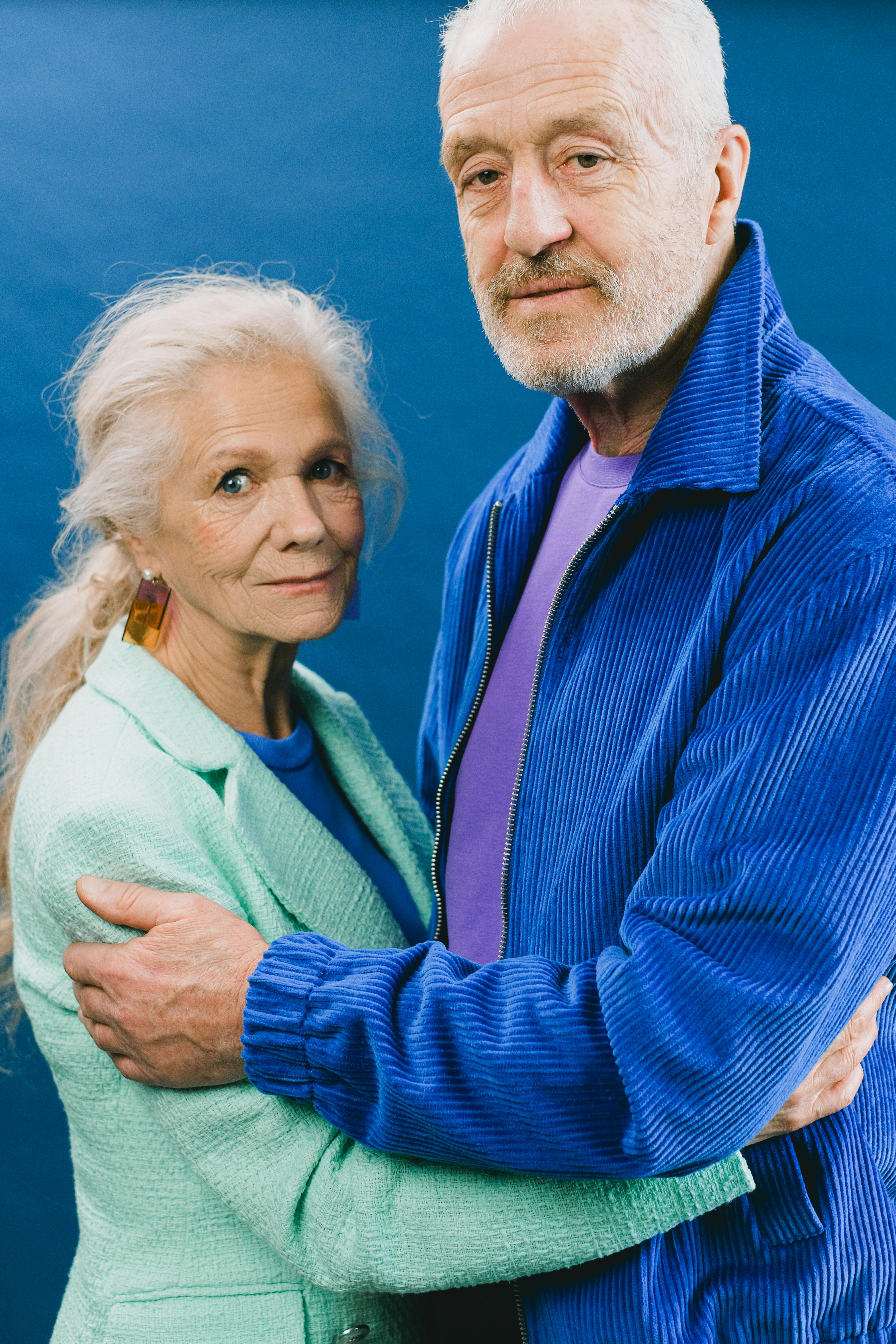Senior couple embracing warmly, showcasing affection and companionship in a studio setting.