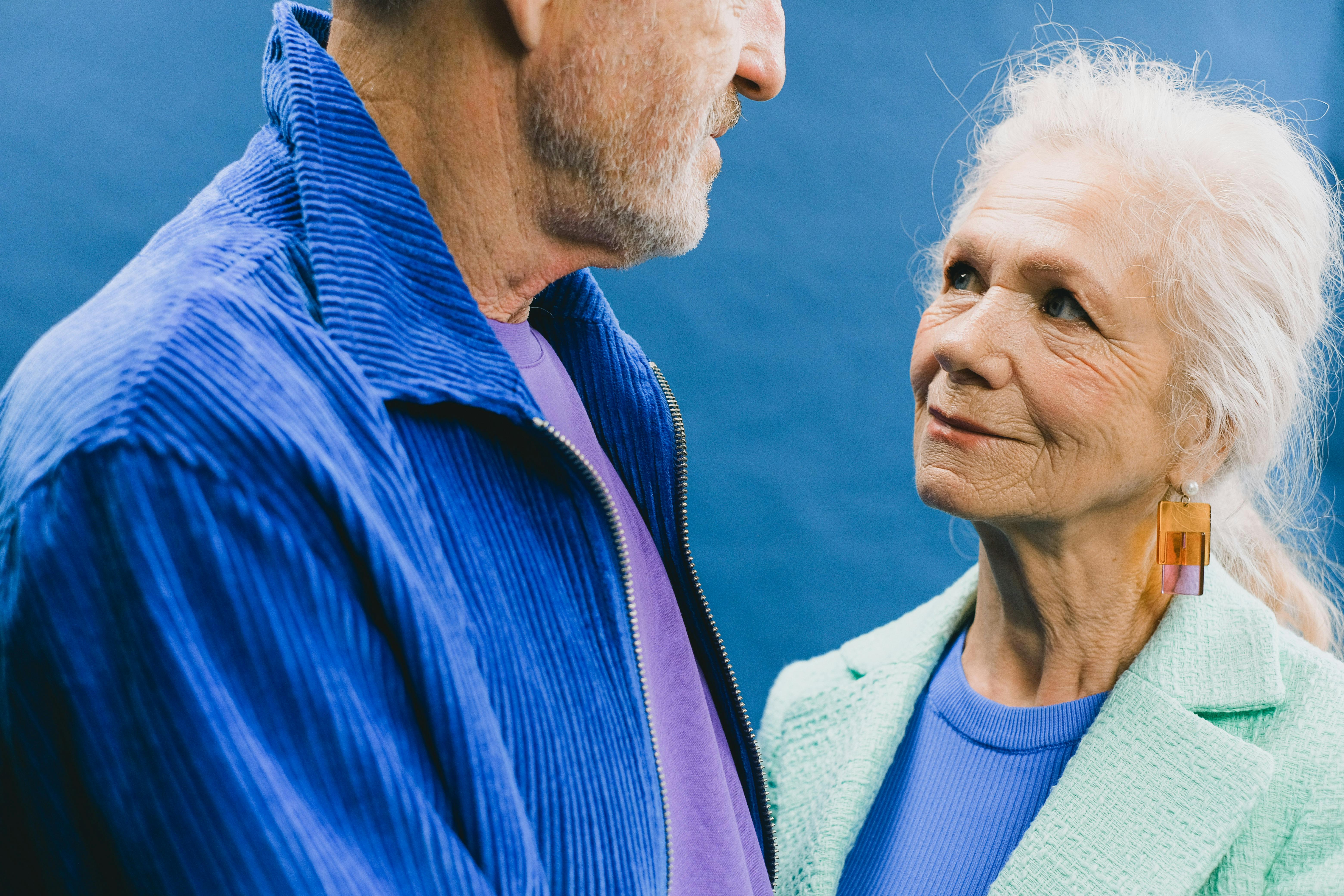 Close-up of an affectionate senior couple gazing at each other in bright clothing.