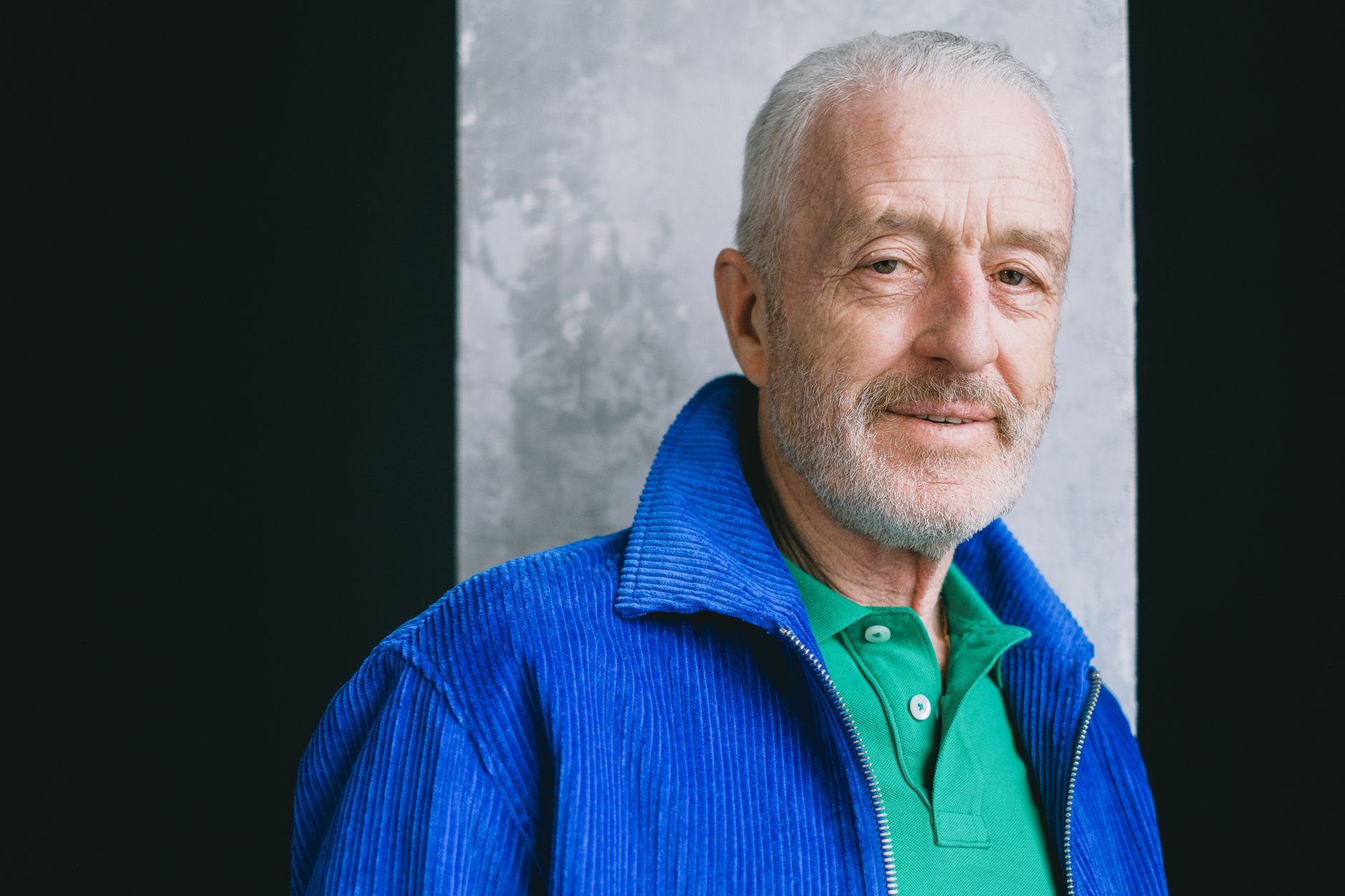 Elderly man smiling in a blue corduroy jacket, portrait.