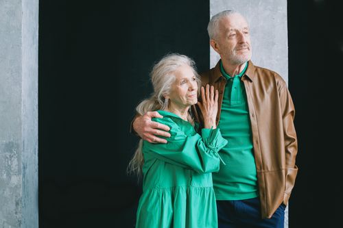 Free An elderly couple standing and embracing, clad in earthy tones, conveying love and togetherness. Stock Photo