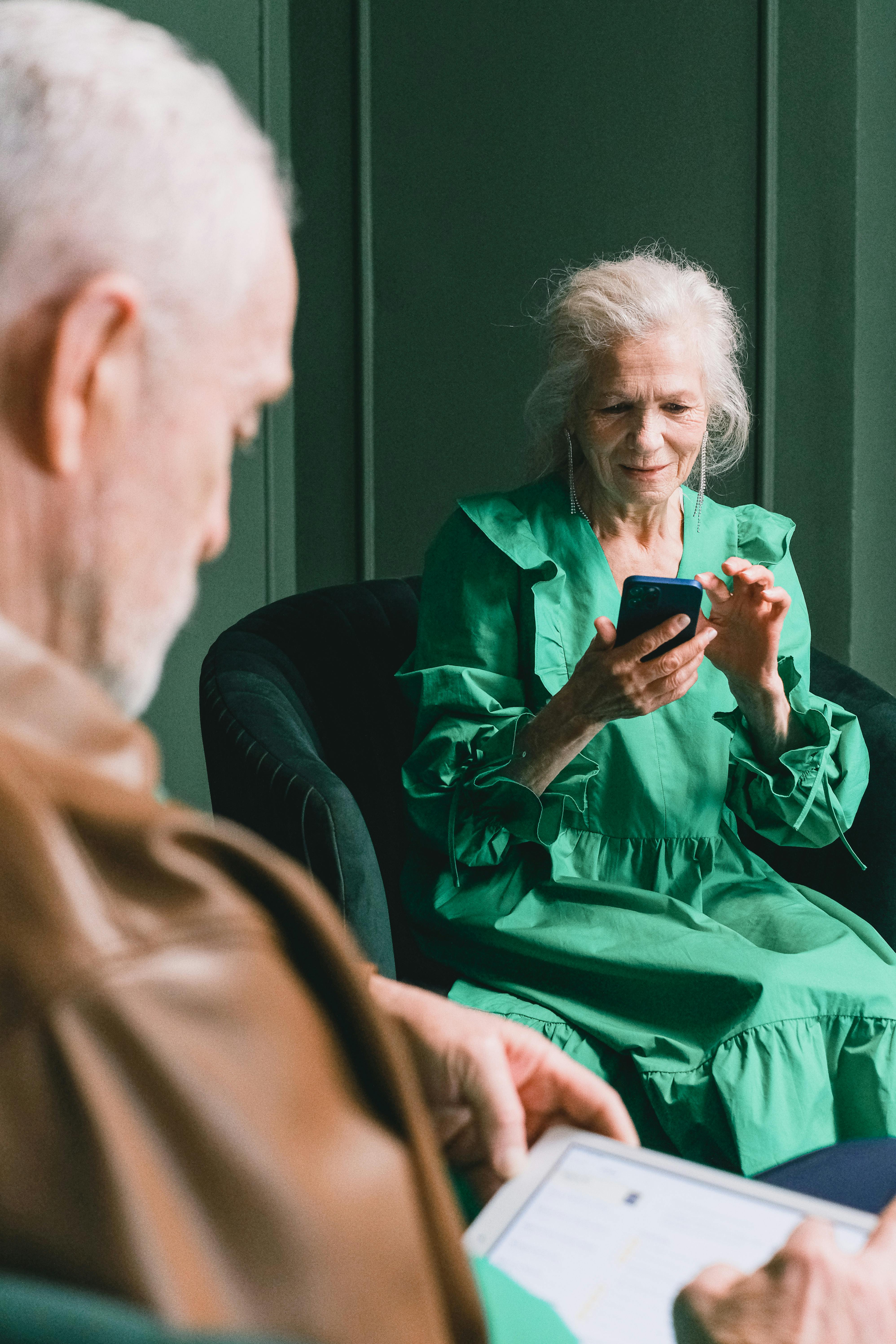 an elderly woman sitting on sofa while using a smartphone