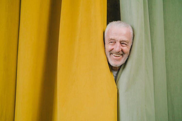 An Elderly Man Sneaking Behind The Curtains