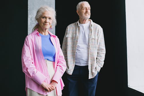 An Elderly Woman in Pink Long Sleeves Smiling while Standing Near the Man in Checkered Long Sleeves