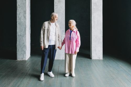 Free A senior couple holding hands in a modern indoor setting, showcasing affection and companionship. Stock Photo