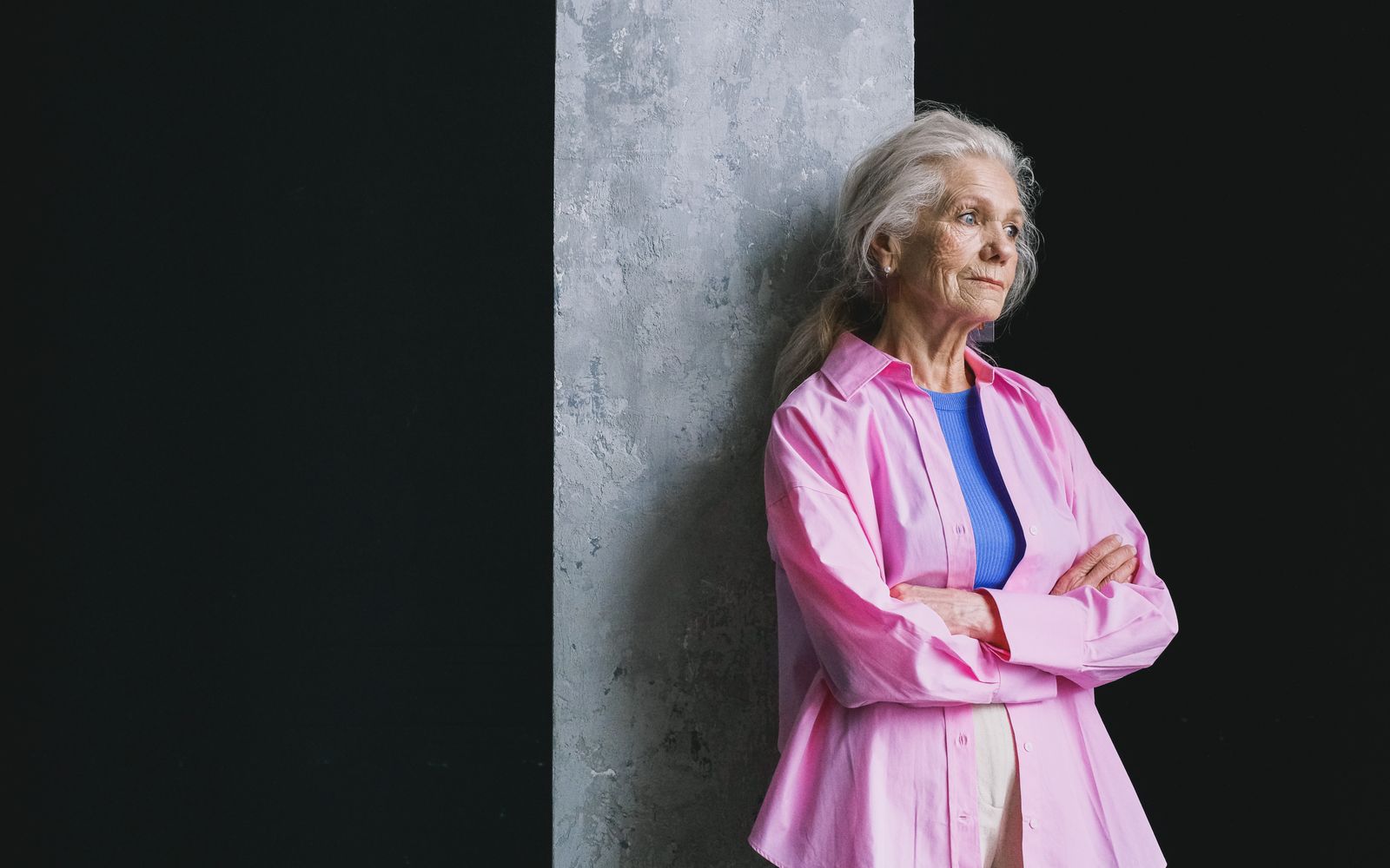Thoughtful senior woman leaning against a wall in deep thought