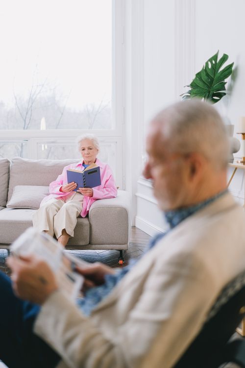 Free A senior couple enjoys reading in a cozy, well-lit living room with modern decor. Stock Photo