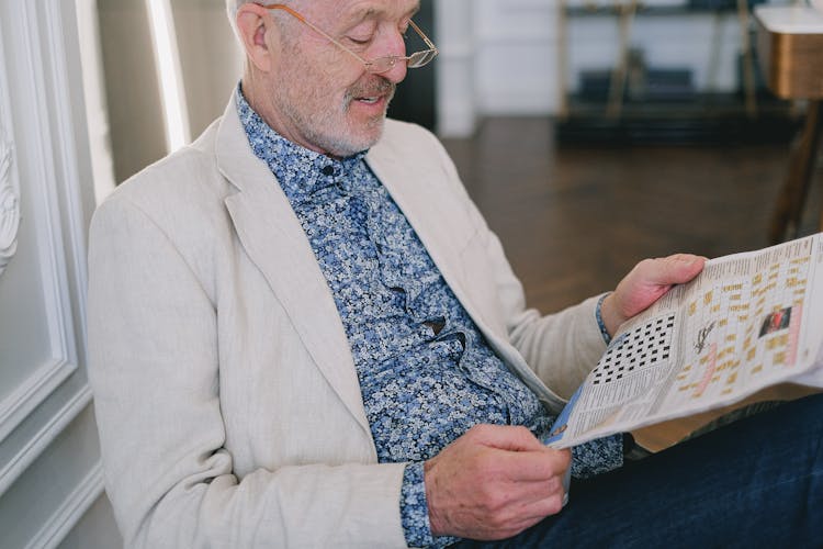 An Elderly Man Reading A Newspaper