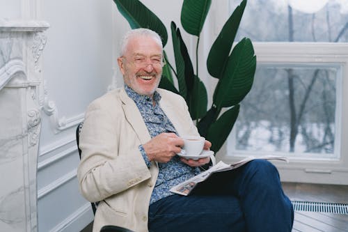 An Elderly Man Laughing while Holding a Cup