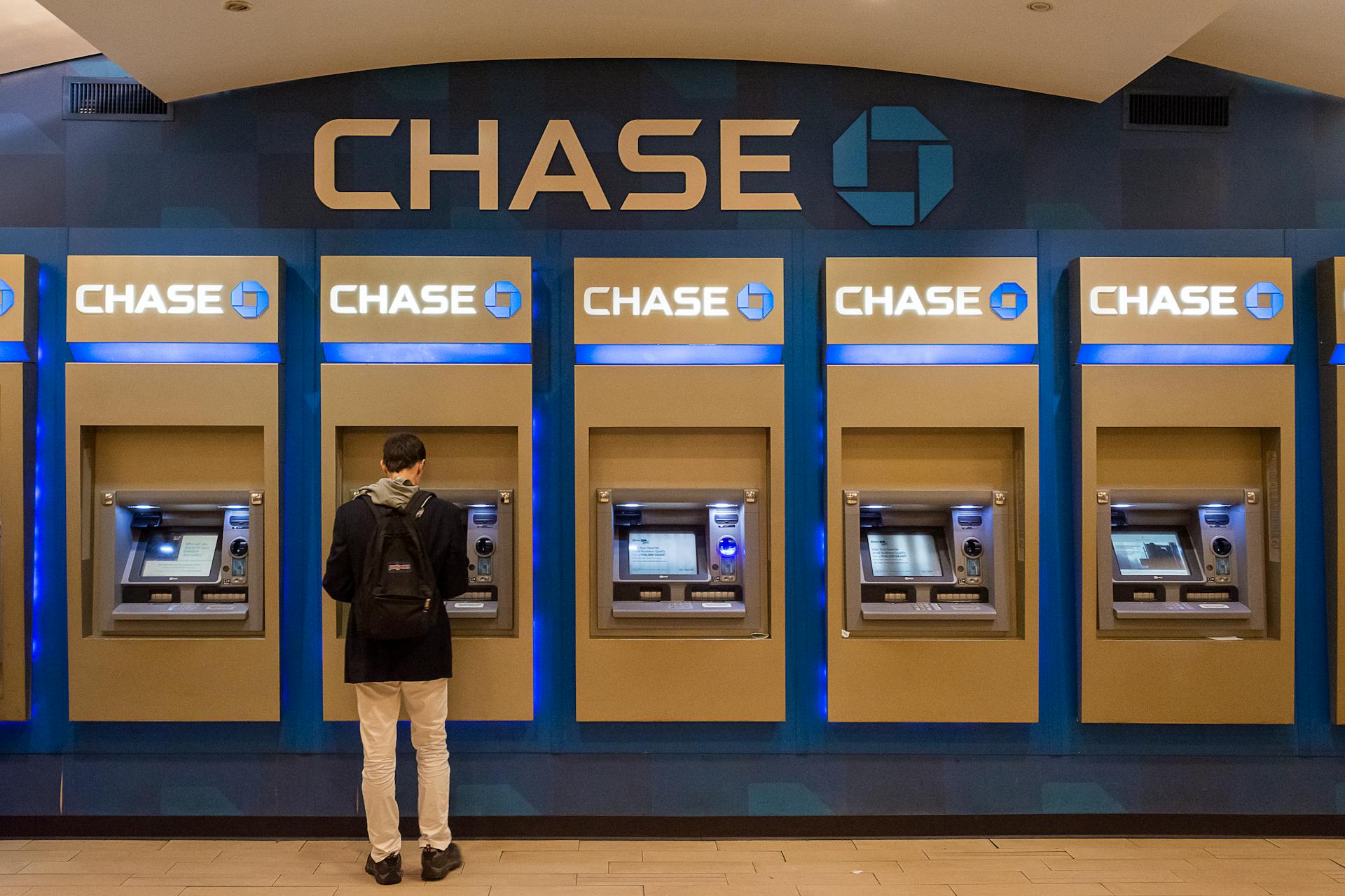 Male customer using Chase ATM machine in an urban indoor setting.