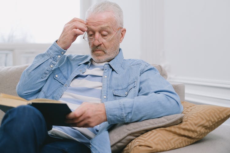 Elderly Man Wearing Denim Long Sleeve While Reading A Book