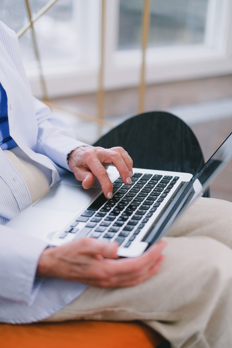Man in a formal shirt typing on a laptop, seated in a modern indoor space.