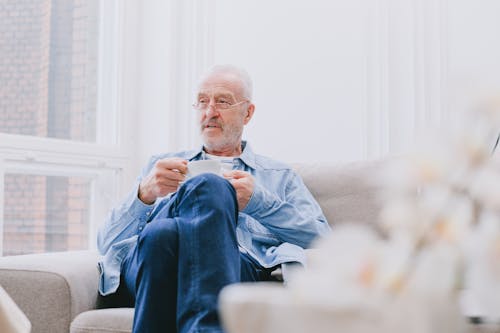 Elderly Man with Eyeglasses Holding a White Cup