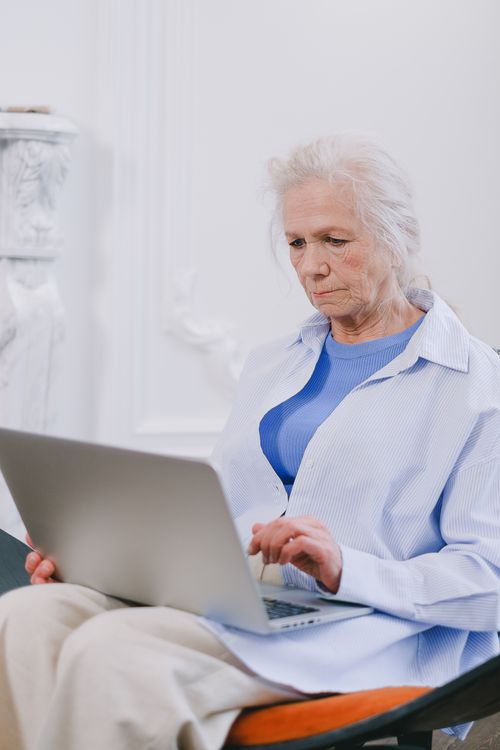Free An elderly woman with white hair using a laptop indoors, showcasing technology use. Stock Photo