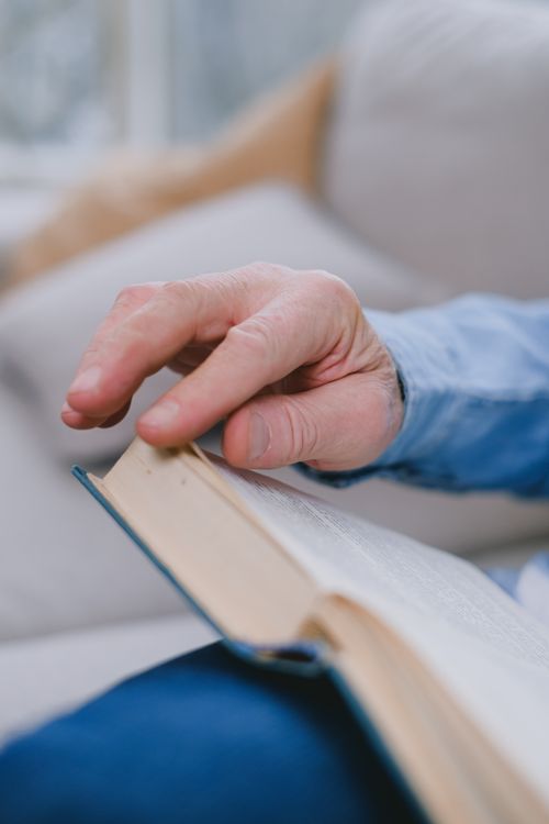 Free Close-up view of a hand turning pages in a cozy setting, emphasizing reading and relaxation. Stock Photo