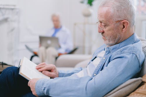 An Elderly Man with Gray Hair Reading a Book