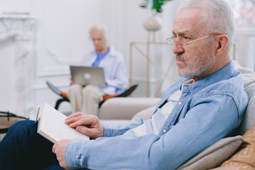Man with Gray Hair Sitting while a Book is on His Lap