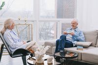 An elderly couple sharing tea in a cozy living room.