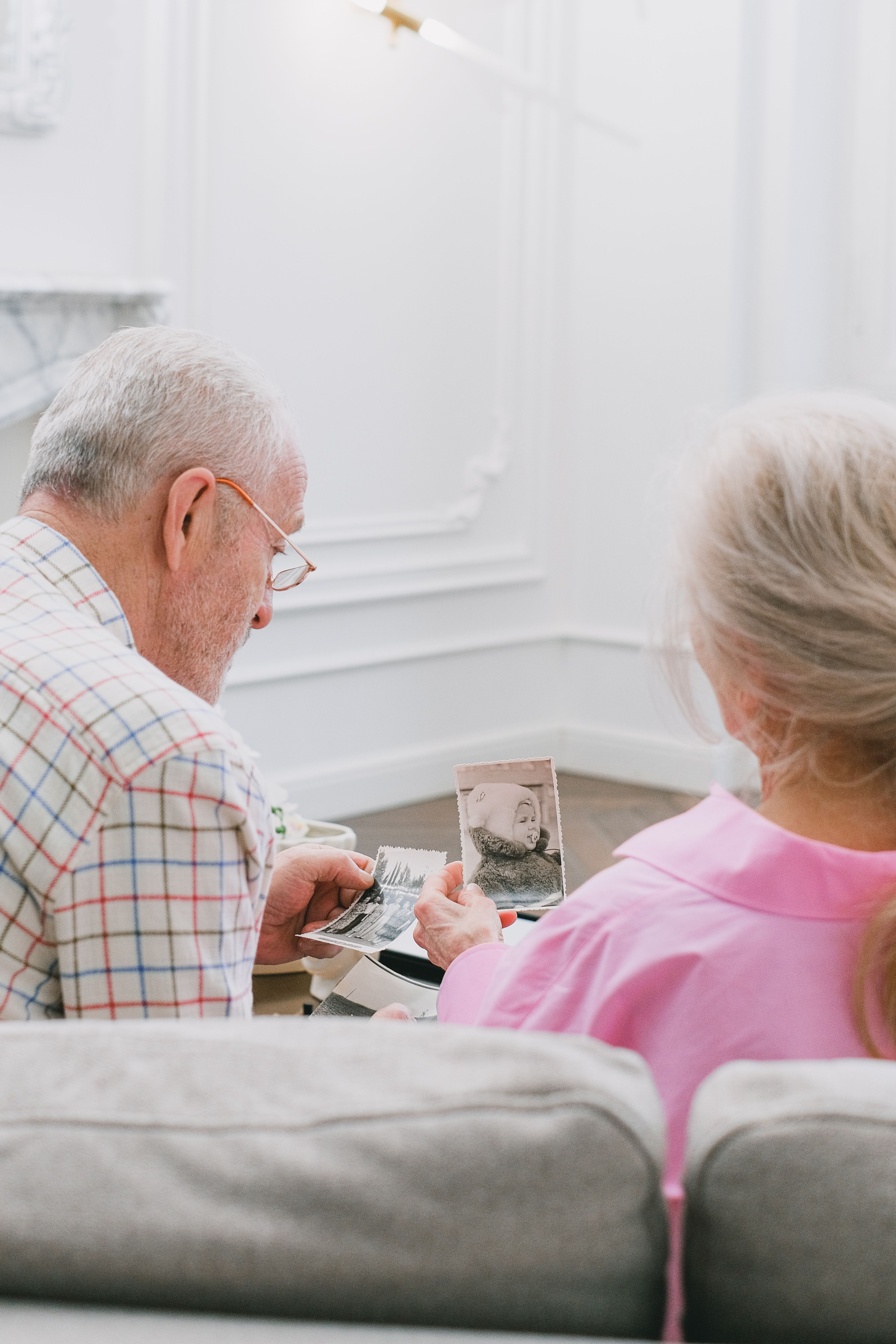 An elderly couple reminiscing while looking at old family photographs.