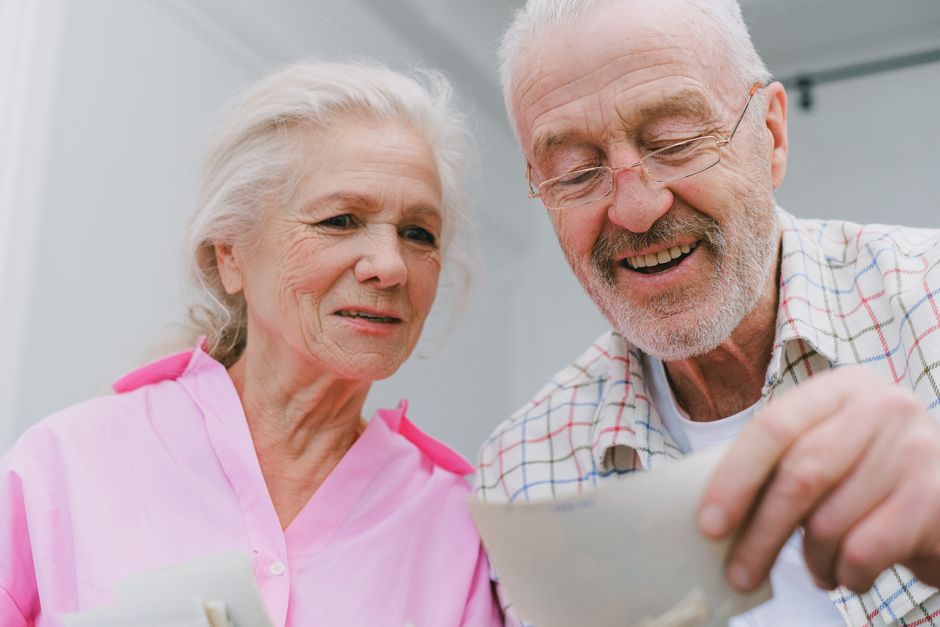 How to Use the DIME Method to Calculate Life Insurance Coverage Happy senior couple enjoying old photographs and sharing memories together.
