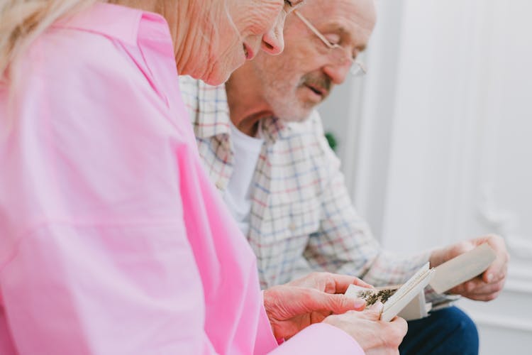 An Elderly Couple With Gray Hair Looking At Photos Together